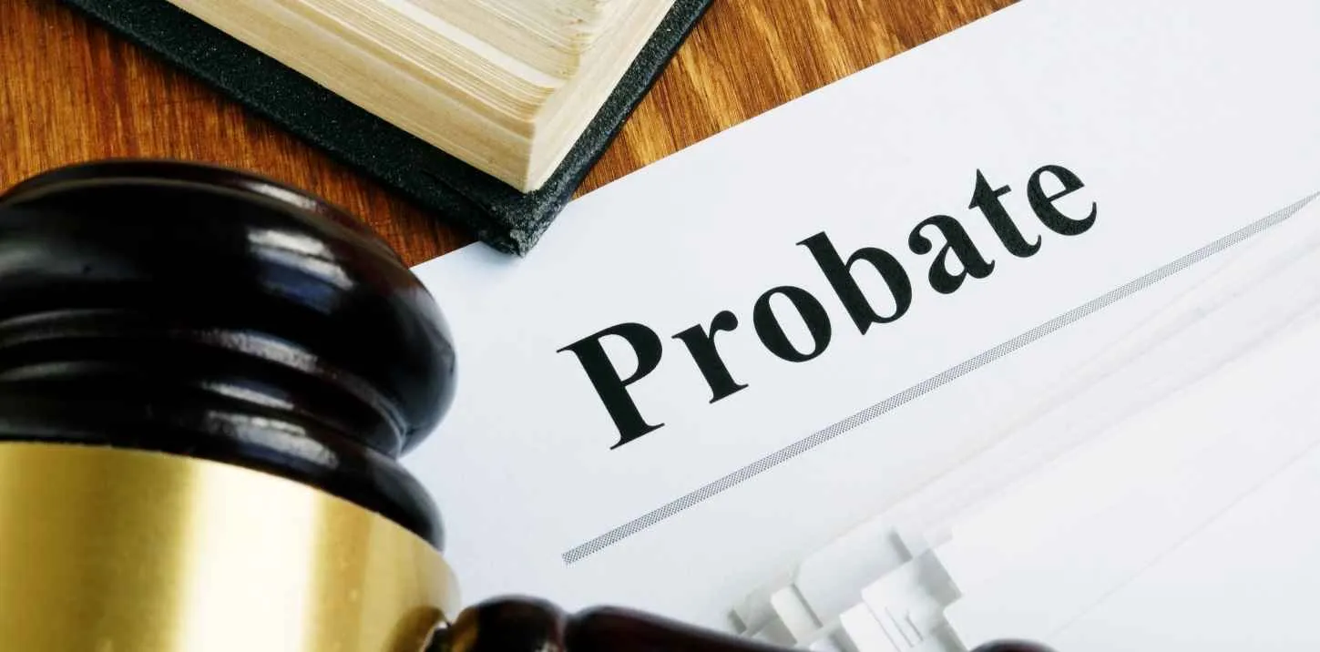 Close-up of a judge's gavel, legal book, and a document titled "Probate" on a wooden surface.