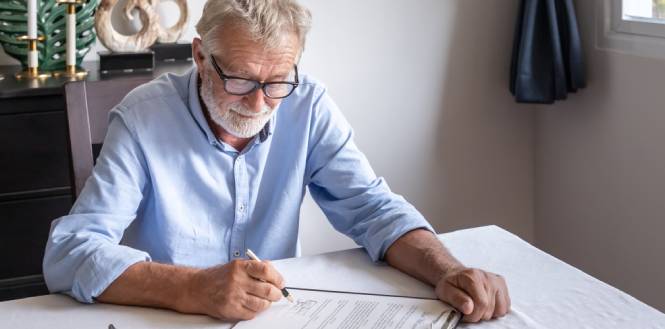 senior old man elderly examining and signing last will and testament