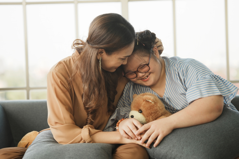 embracing child to encourage down syndrome girl at home