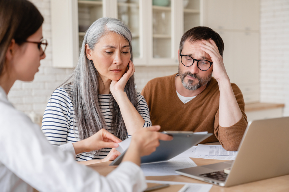 financial advisor lawyer consulting mature middle-aged couple showing them debts