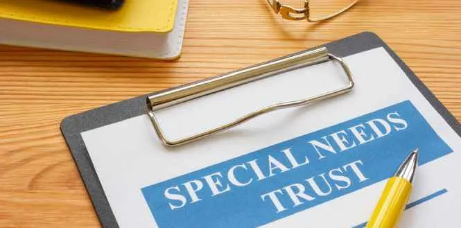 Clipboard with document titled "Special Needs Trust" and a yellow pen on wooden table.