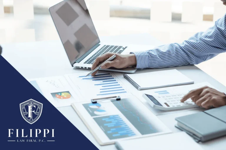 Professional working at desk with laptop, financial charts, calculator, and Filippi Law Firm logo.