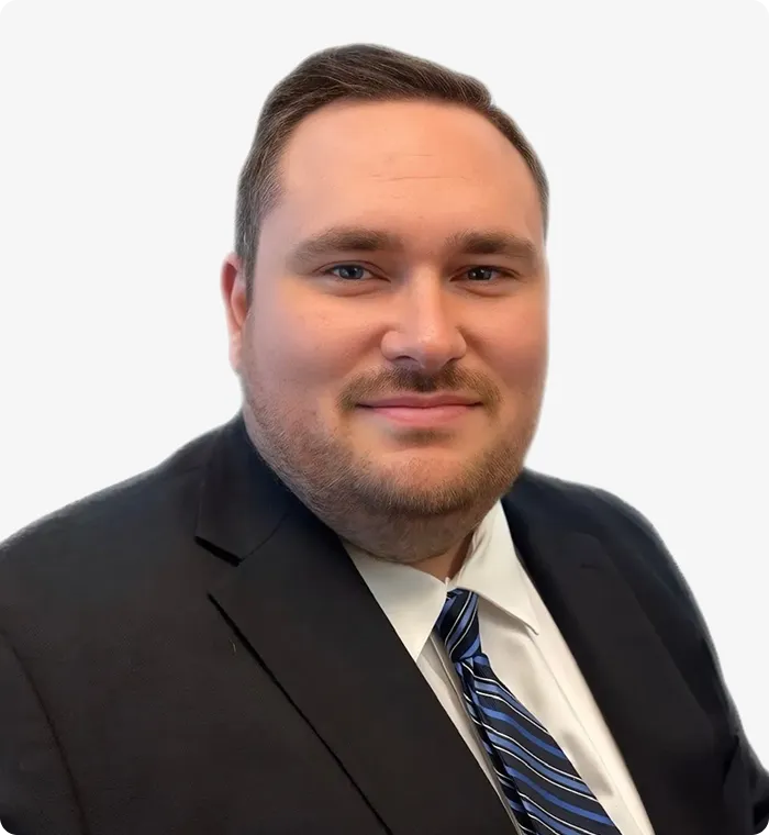 Professional headshot of a man in a dark suit, white shirt, and blue striped tie.
