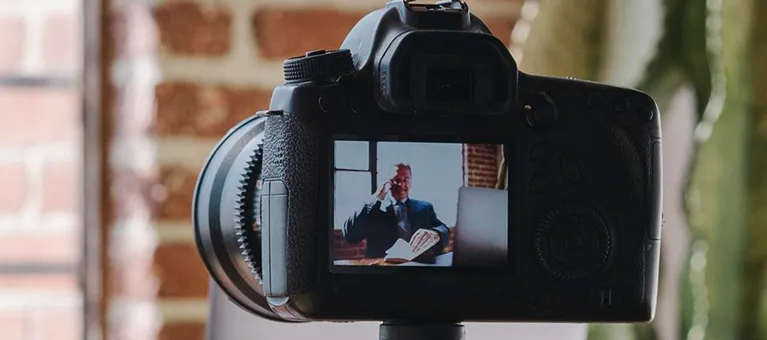 Digital camera screen displaying a man in a suit speaking on the phone, with a brick wall background.