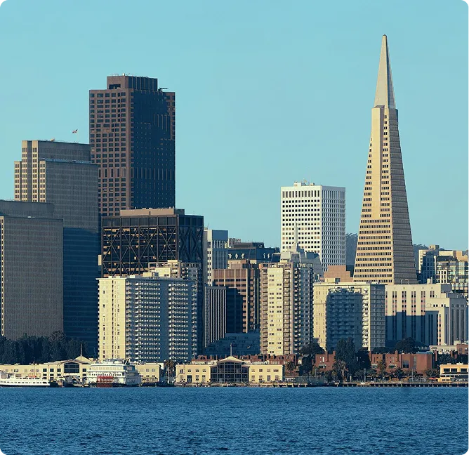 City skyline featuring high-rise buildings and the Transamerica Pyramid under a clear blue sky.