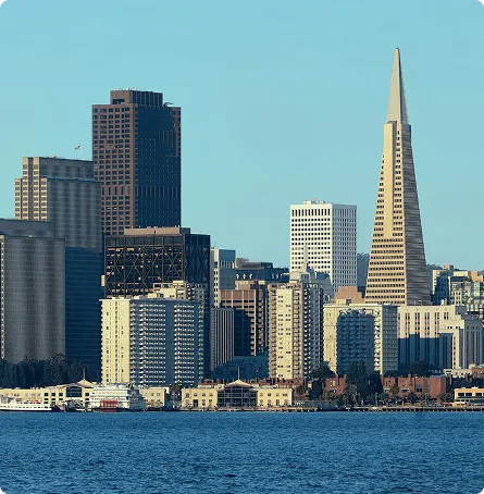 View of San Francisco skyline with Transamerica Pyramid and waterfront under clear sky.