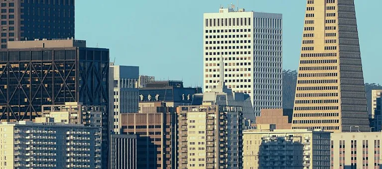 Cityscape featuring diverse modern skyscrapers and office buildings under clear blue sky.
