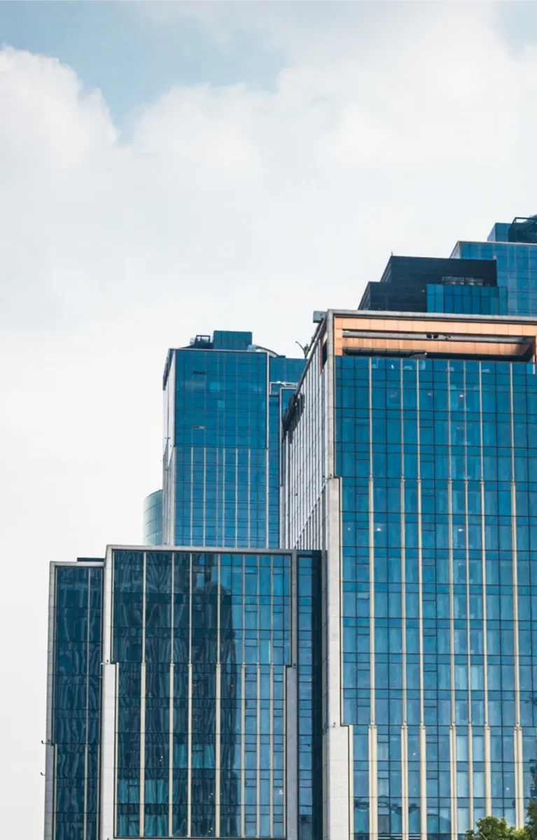 Modern blue-glass skyscrapers with reflective windows under a cloudy sky.
