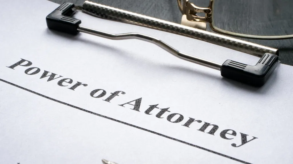 Close-up of a Power of Attorney document on a clipboard with eyeglasses resting above.