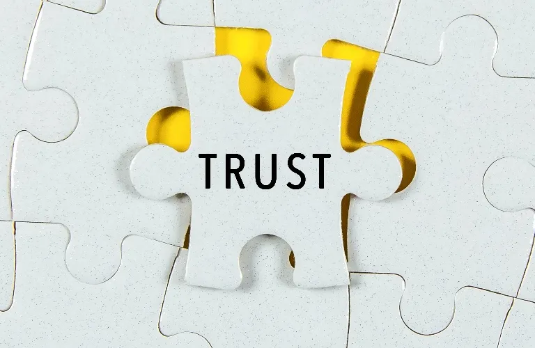 White jigsaw puzzle piece with the word "TRUST" over a yellow background.