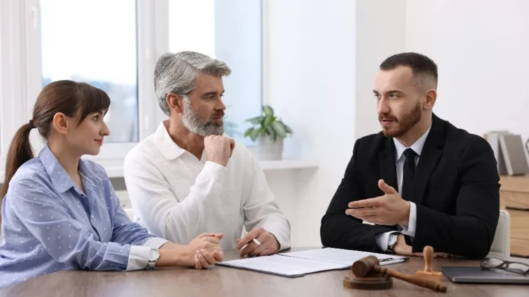 Three professionals engaged in a discussion at a table with legal documents and a gavel.