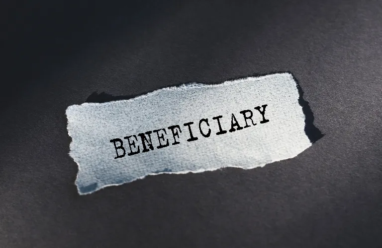 Torn white paper with the word "BENEFICIARY" typed in black on a dark surface.